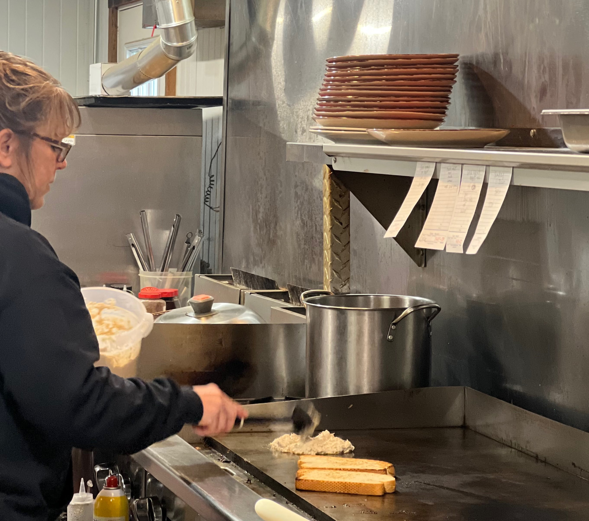 Tracy cooking hash browns and toast on the flat-top griddle