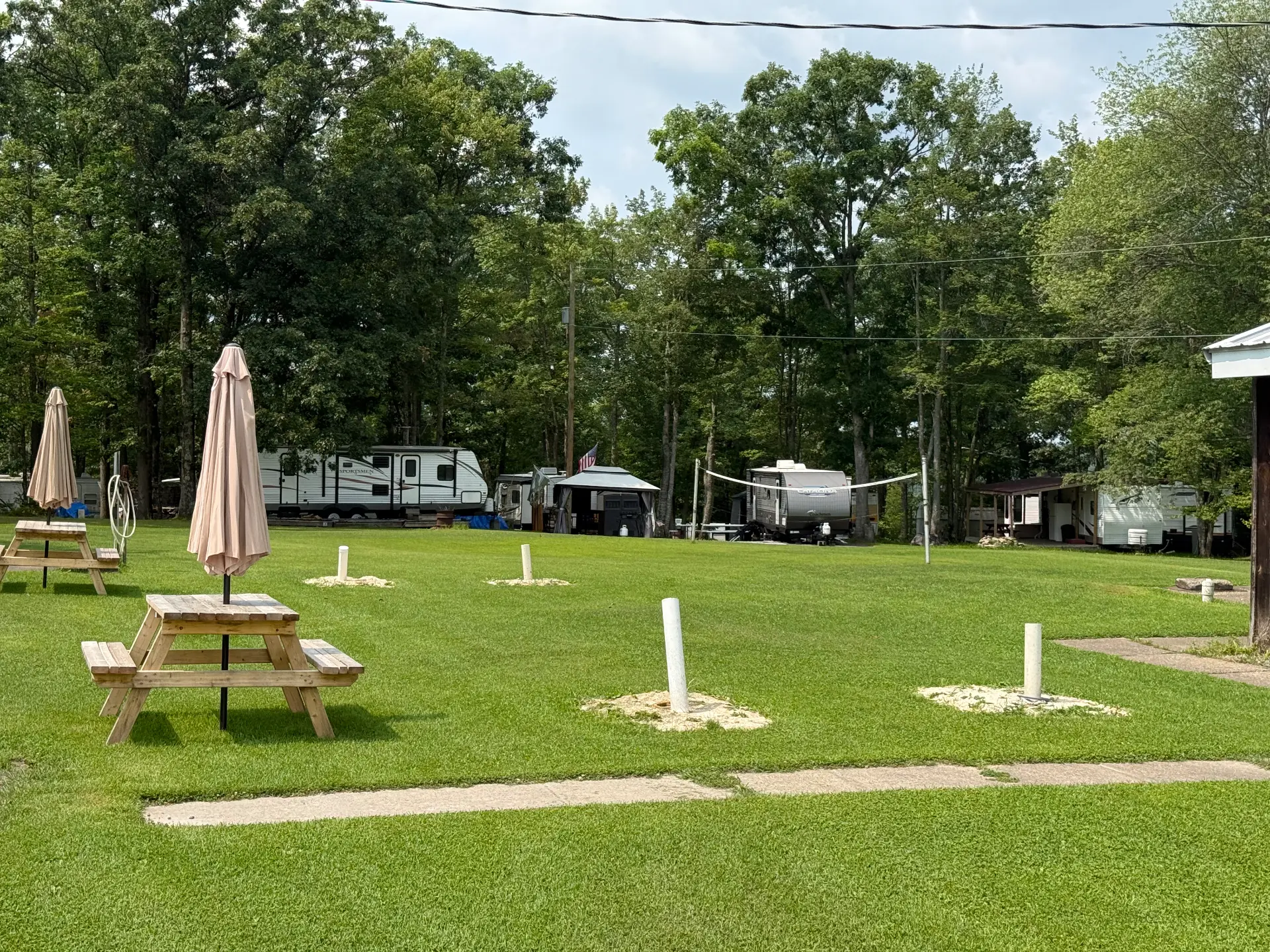 Open lawn with volleyball net, horseshoe pits and shaded picnic tables